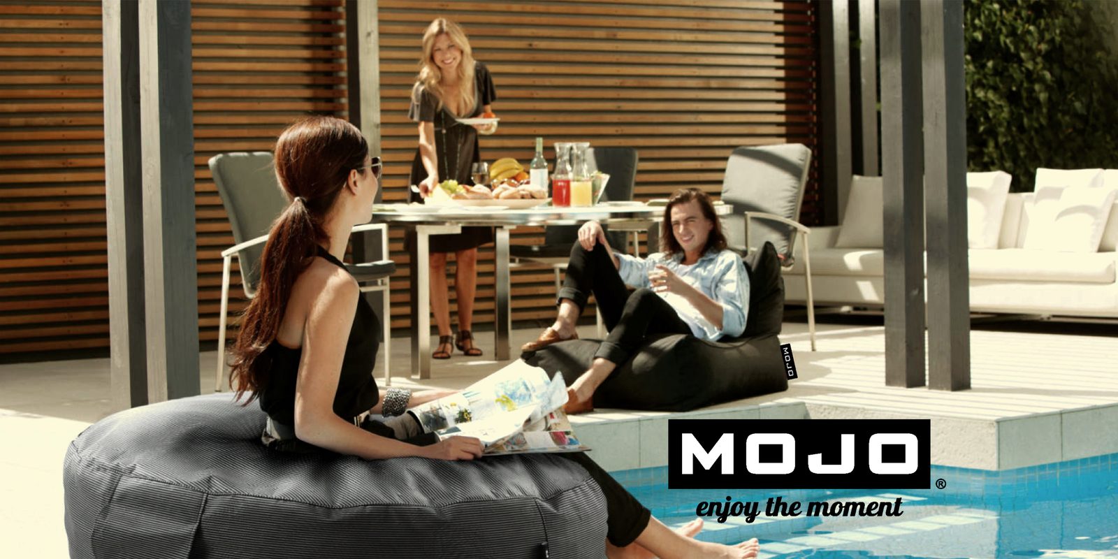 People relaxing on black Mojo bean bags beside a pool, with the Mojo logo